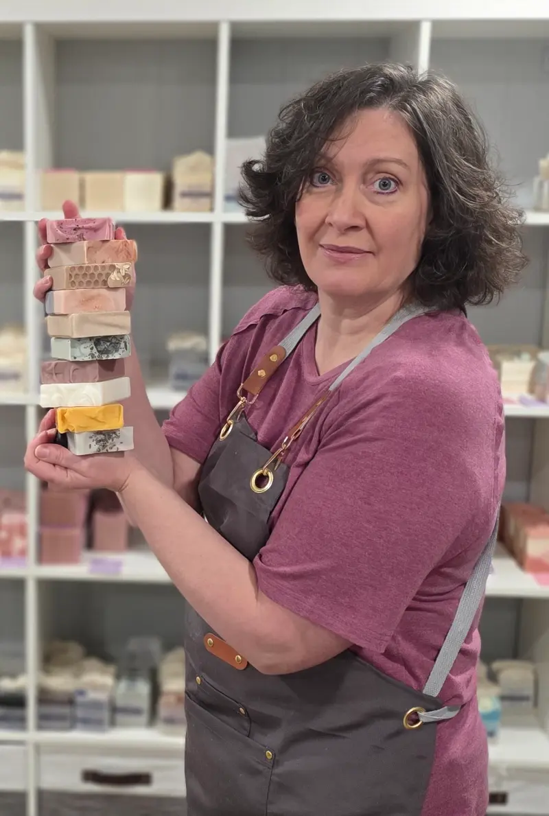 Kim, the owner, holding a stack of handmade soap.