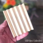Curved alder wood soap dish with a handmade bar of soap resting on the slotted surface