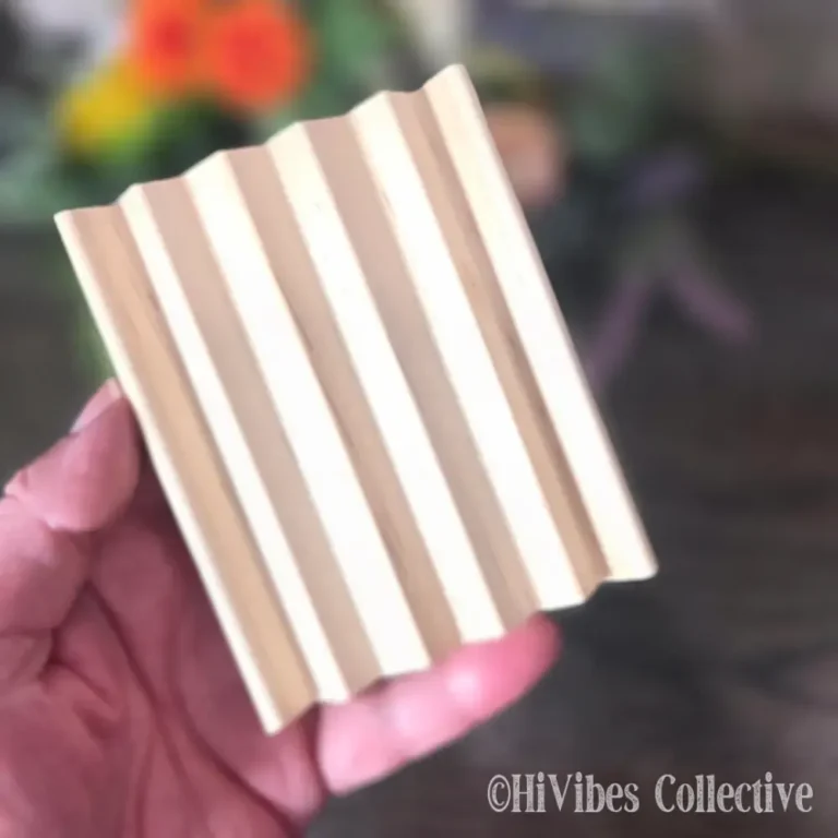 Curved alder wood soap dish with a handmade bar of soap resting on the slotted surface