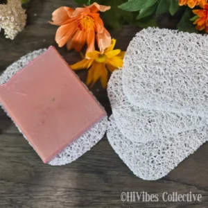 Light grey plastic soap saver pad with a handmade bar of soap resting on its textured open surface
