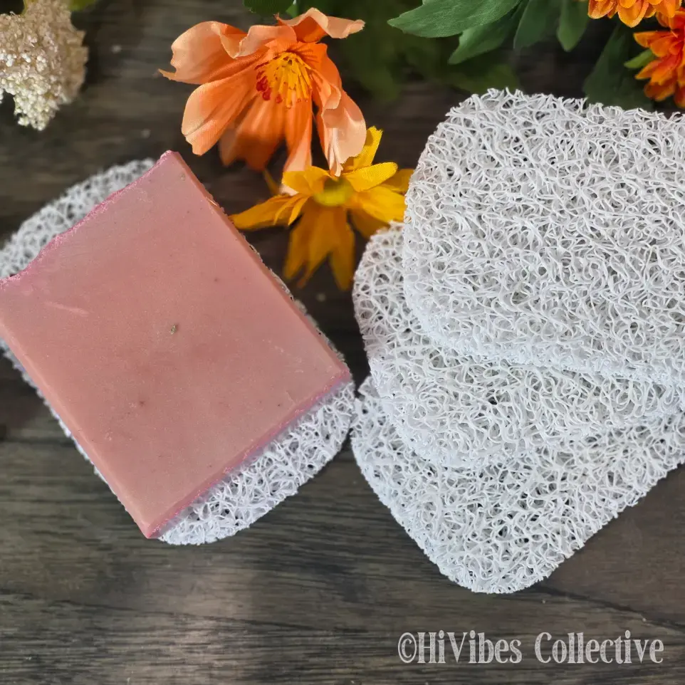 Light grey plastic soap saver pad with a handmade bar of soap resting on its textured open surface