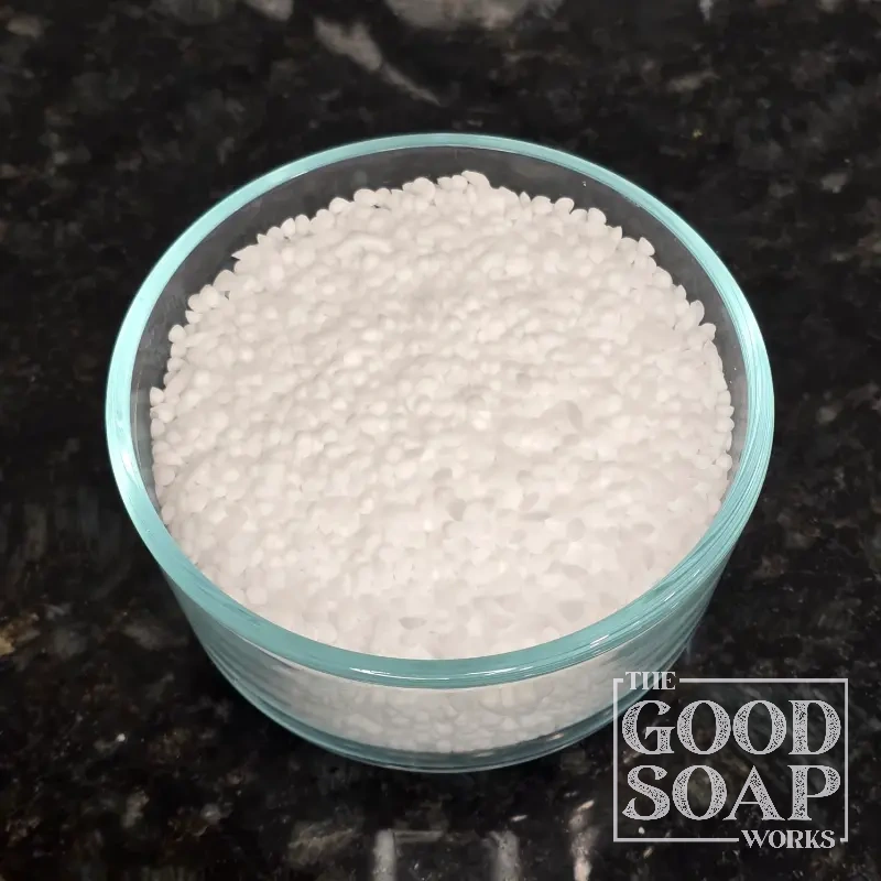 Cetearyl Alcohol pastilles displayed in a small bowl, an emollient ingredient used in skincare by The Good Soap Works Co.