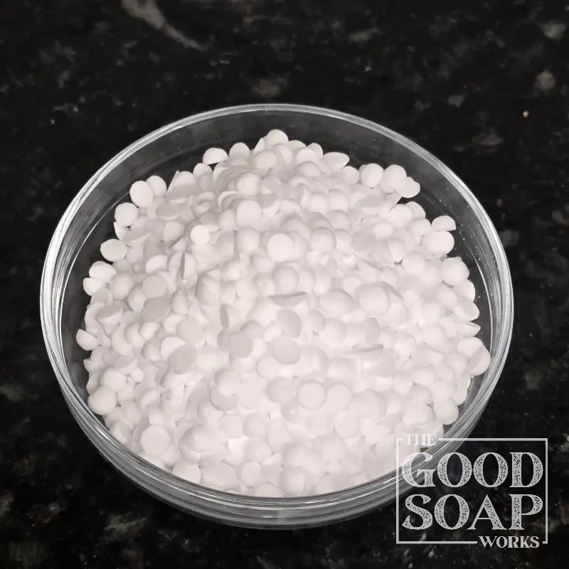 Cetyl Alcohol pastilles displayed in a small bowl, an emollient ingredient used in skincare by The Good Soap Works Co.