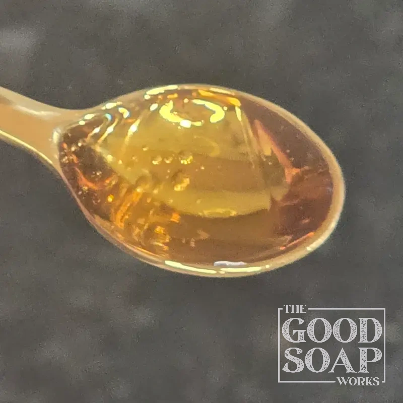 Neem oil on a wooden spoon — a pungent botanical oil used in natural soap and skin care formulations