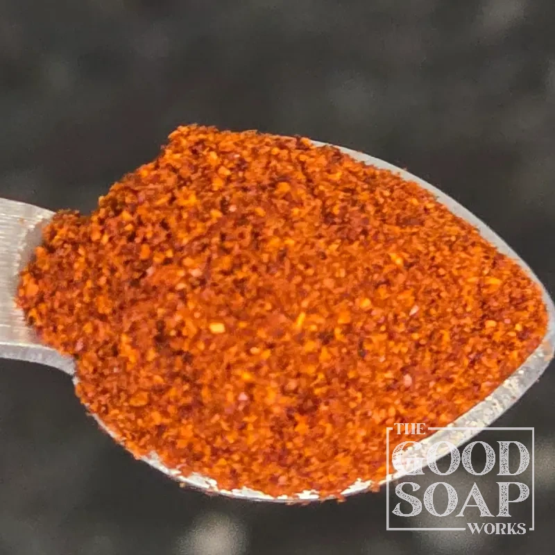 Paprika powder on a wooden spoon — a warm natural colorant used in handmade soap making