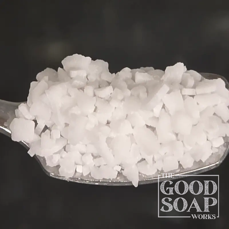 Potassium hydroxide lye on a wooden spoon — the alkali used to make liquid soap and soft soap