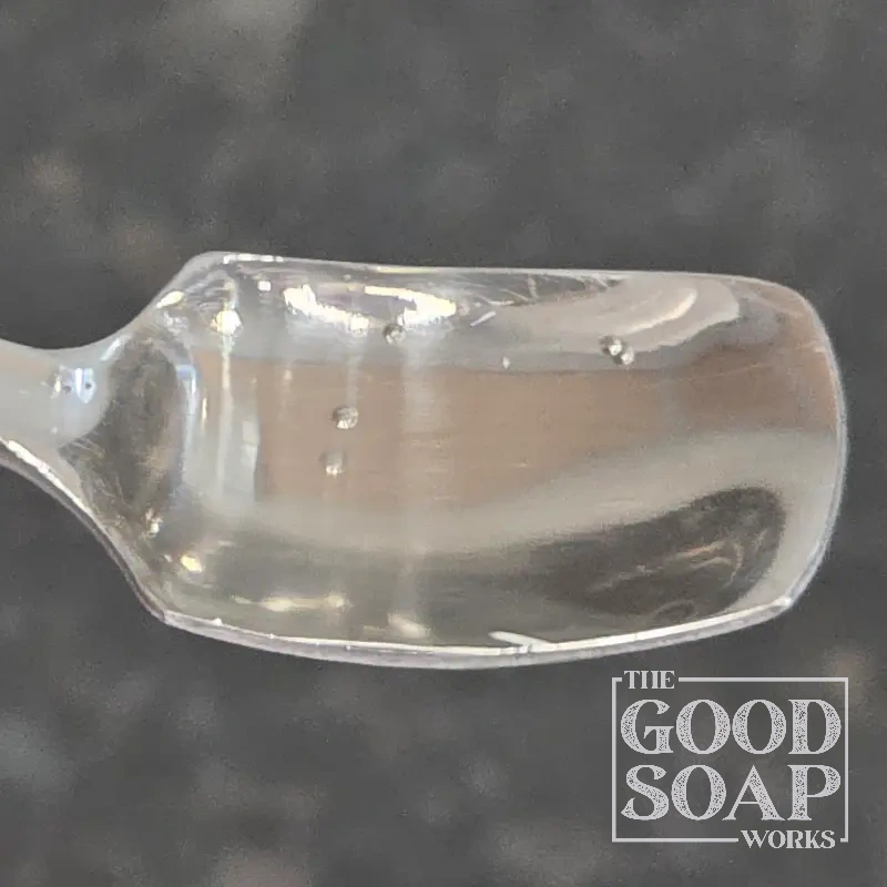 Pumpkin seed oil on a wooden spoon — a deep green botanical oil used in natural soap and facial care