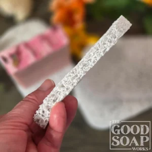 Light grey plastic soap saver pad with a handmade bar of soap resting on its textured open surface and a closeup view of the thickness of the pad