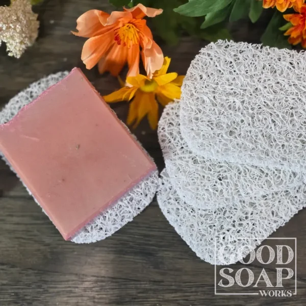 Light grey plastic soap saver pad with a handmade bar of soap resting on its textured open surface
