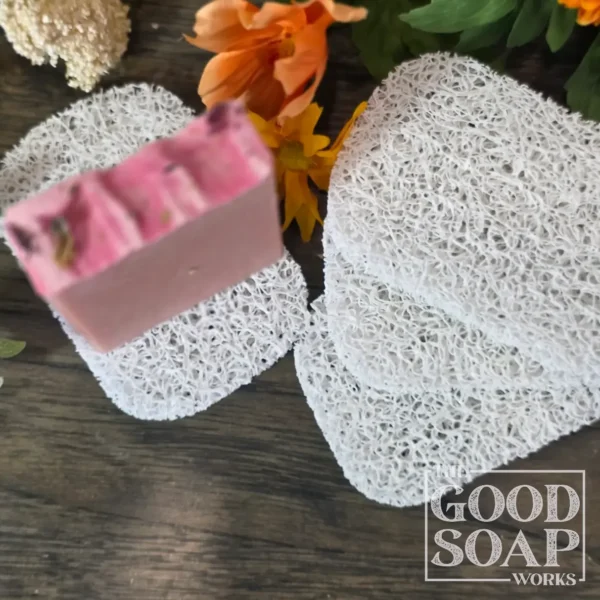 Light grey plastic soap saver pad with a handmade bar of soap resting on its textured open surface