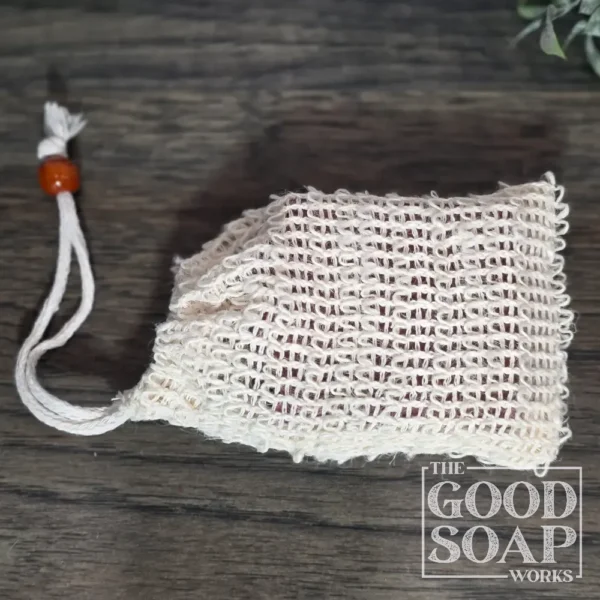 Natural sisal soap saver bag with drawstring closure holding a bar of handmade soap